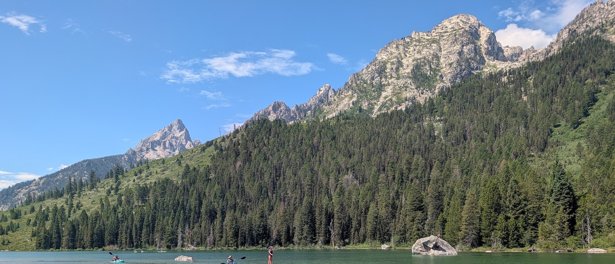 The turquoise shallows of String Lake with kayakers and a paddleboarder